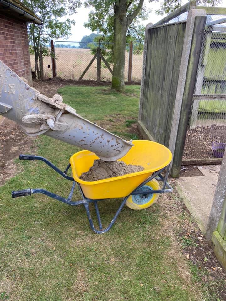 Cement mixer filling yellow wheel barrow